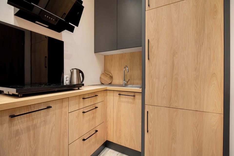 A close-up of a kitchen corner with wooden cabinetry. Built-in appliances are neatly integrated. The surfaces appear clean and well-maintained.