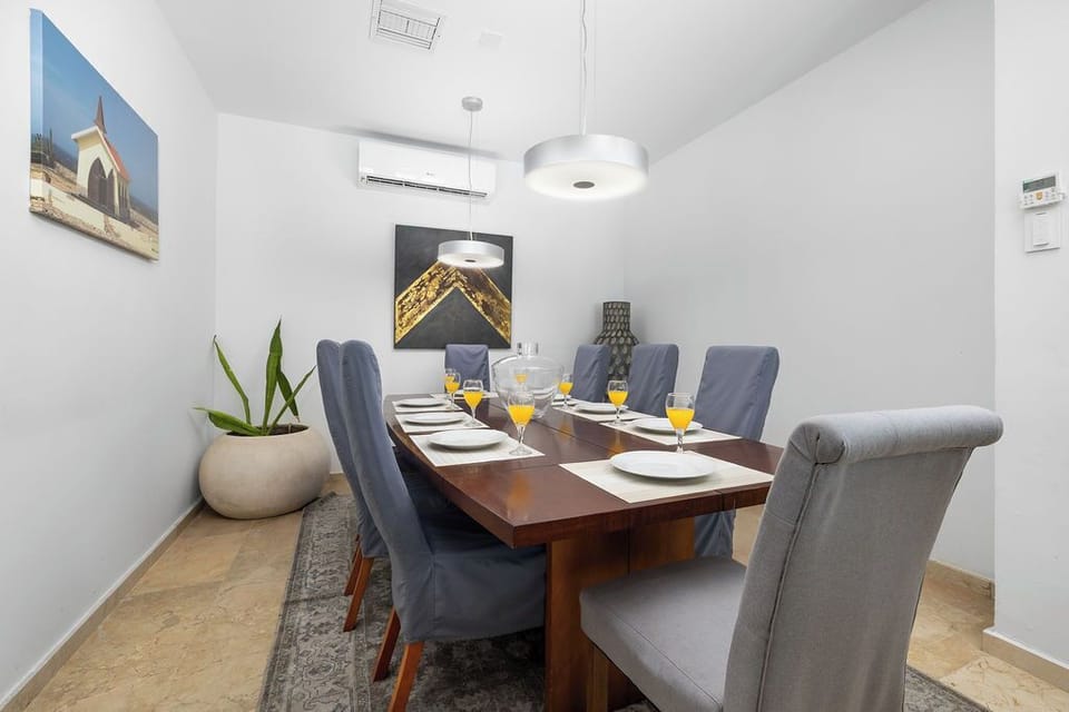 Gather around this elegant dining table where memories are made—crisp white linens, plush gray chairs, and modern lighting create the perfect setting for your group meals and lively conversations.
