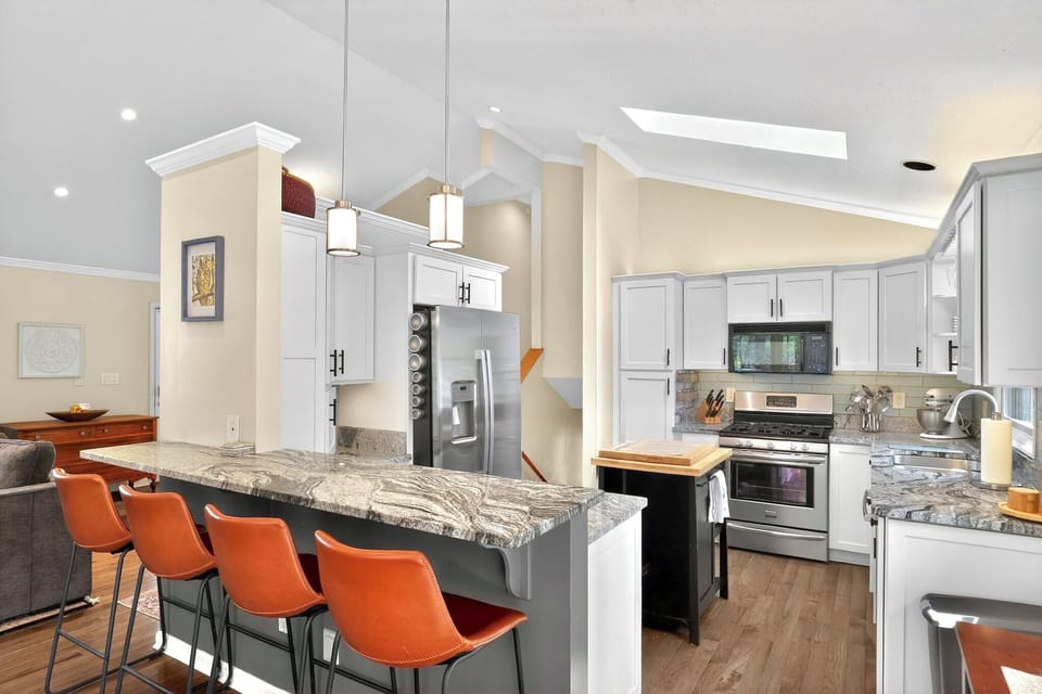 Bright vaulted kitchen with skylight, granite island, and bar seating