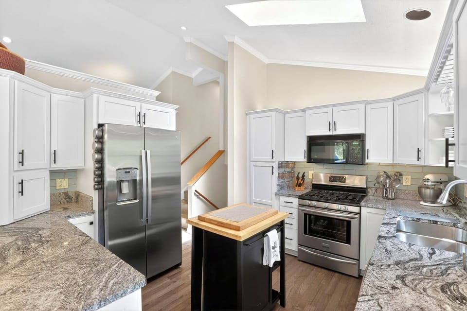 Bright gourmet kitchen with granite counters, skylight, and stainless appliances