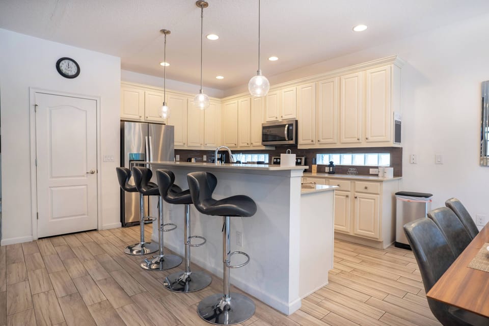 Enjoy a sleek kitchen with stylish white cabinetry and modern stainless-steel appliances. The chic breakfast bar with four contoured stools invites casual meals and great conversations in a welcoming atmosphere.
