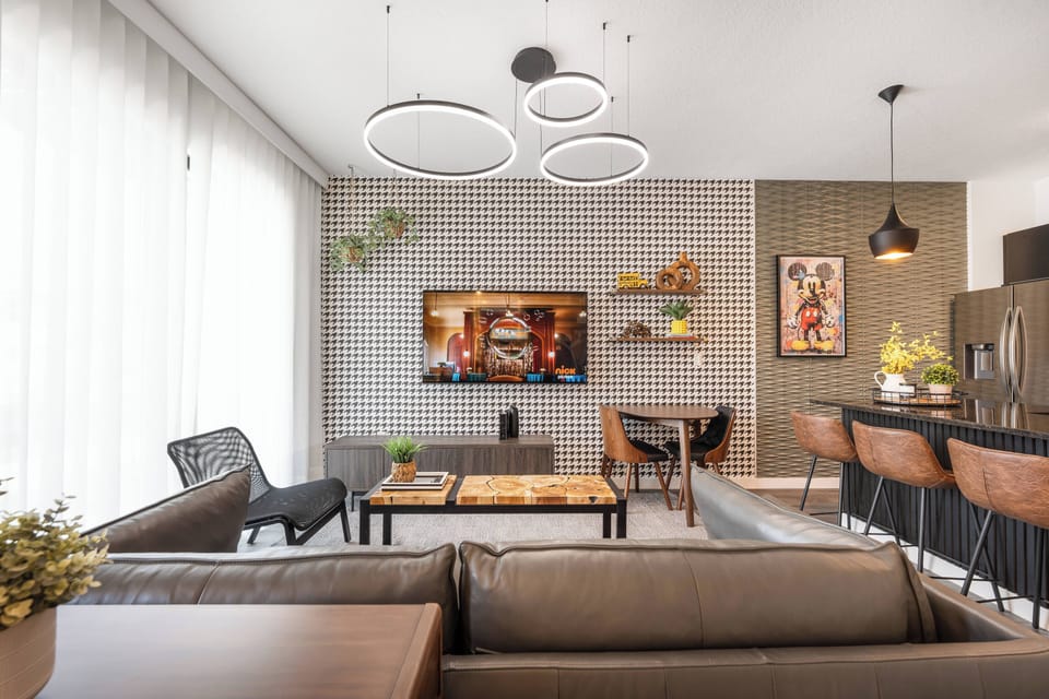 Enjoy a beautifully designed living area where modern style meets comfort. The patterned accent wall and sleek light fixtures welcome you, while plush seating and a wood coffee table offer a warm space for relaxation or.
