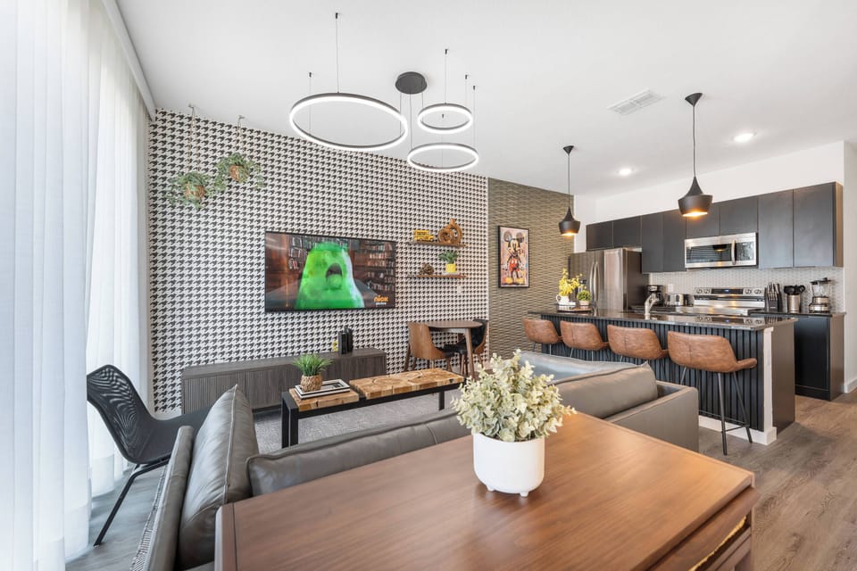 Relax in a spacious living area with a stunning geometric accent wall and stylish furnishings. Enjoy your favorite shows on the comfortable sofa while basking in natural light from the large windows.