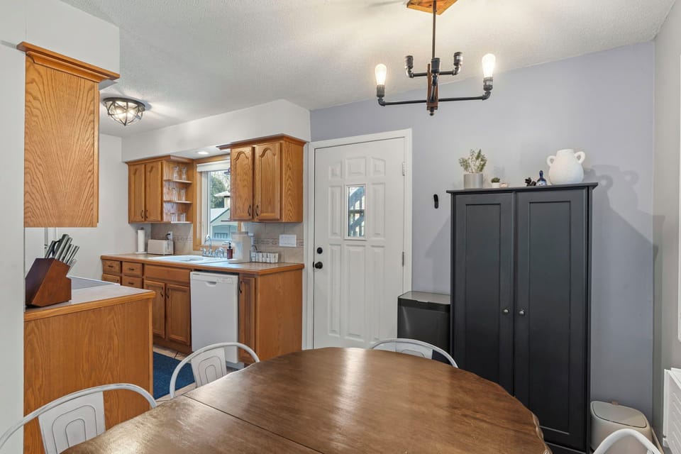 Your fully equipped kitchen flows seamlessly into the dining space, perfect for preparing meals and gathering around the warm wood table.