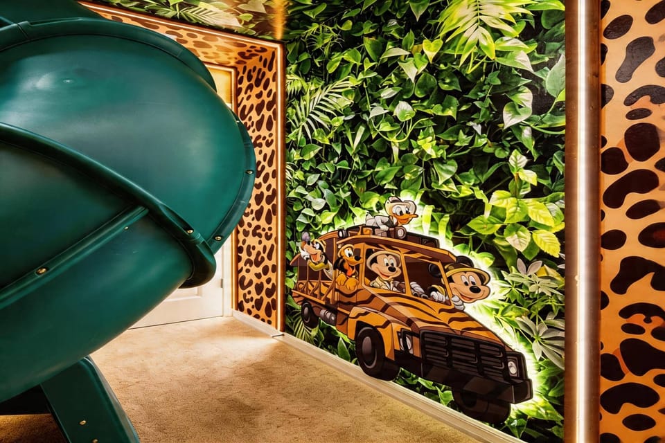 Enjoy a playful safari themed bunk room with cozy bunk beds, a fun indoor slide, jungle ceiling details, warm lighting, and soft carpet, creating an exciting space for kids during vacation.