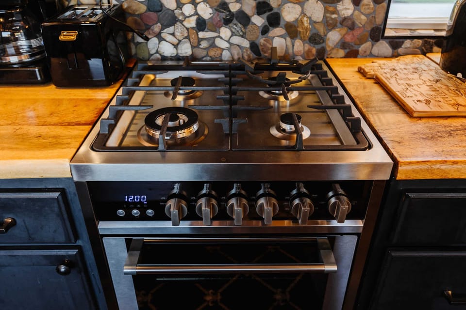 Fully equipped kitchen with wood countertops, modern appliances, a gas range, and stylish cabinetry. Bright windows and thoughtful design make cooking easy, functional, and enjoyable in this cozy tiny home.