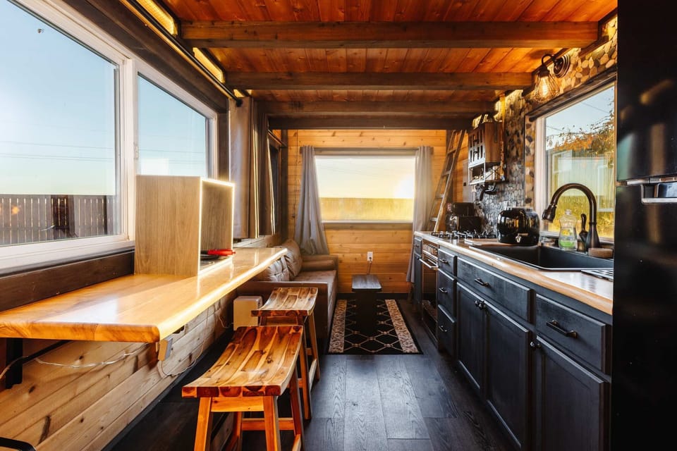 Fully equipped kitchen with wood countertops, modern appliances, a gas range, and stylish cabinetry. Bright windows and thoughtful design make cooking easy, functional, and enjoyable in this cozy tiny home.
