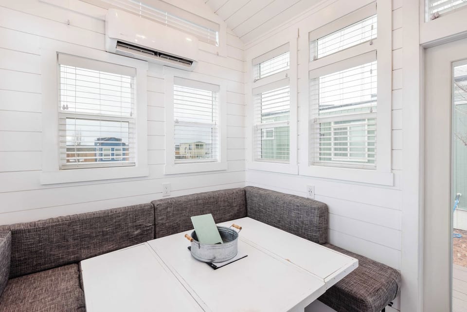 Bright dining nook with wraparound seating that converts into a comfortable sofa bed. Surrounded by large windows for natural light, with AC/heat for year-round comfort.  Perfect for relaxing, dining, or extra sleeping space.