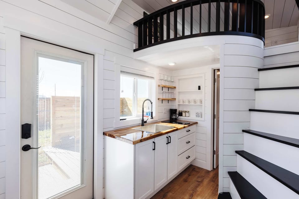Bright kitchen with warm wood countertops, ample cabinet storage, and stairs leading to the loft sleeping area.