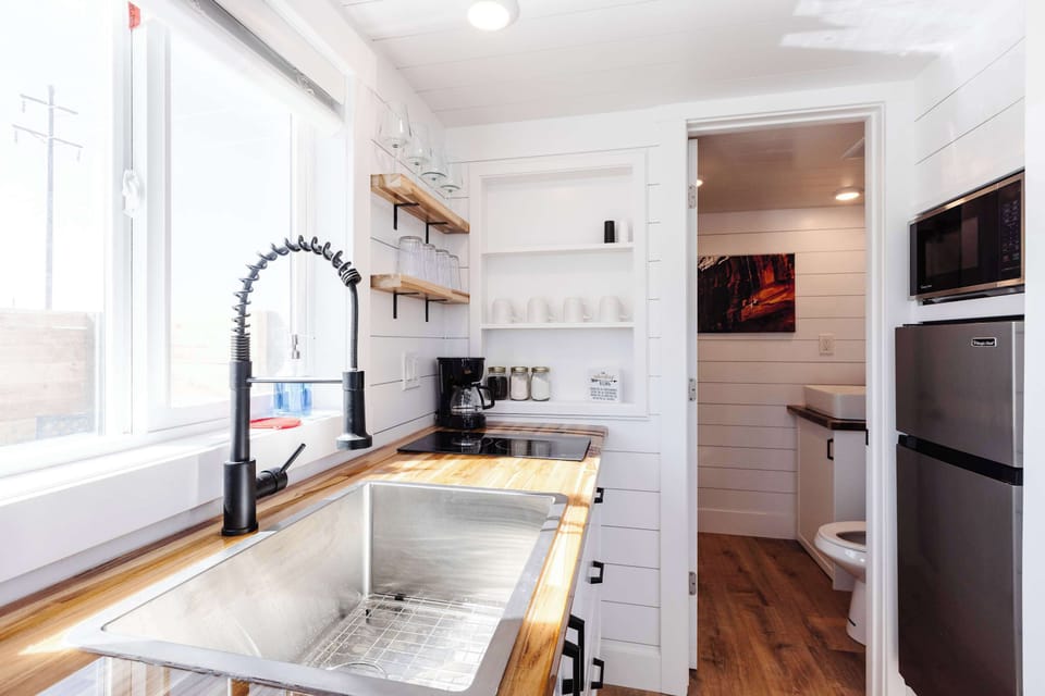 Compact, well-designed kitchen with refrigerator and freezer, microwave, cooktop, large sink, and plenty of counter space for preparing meals.