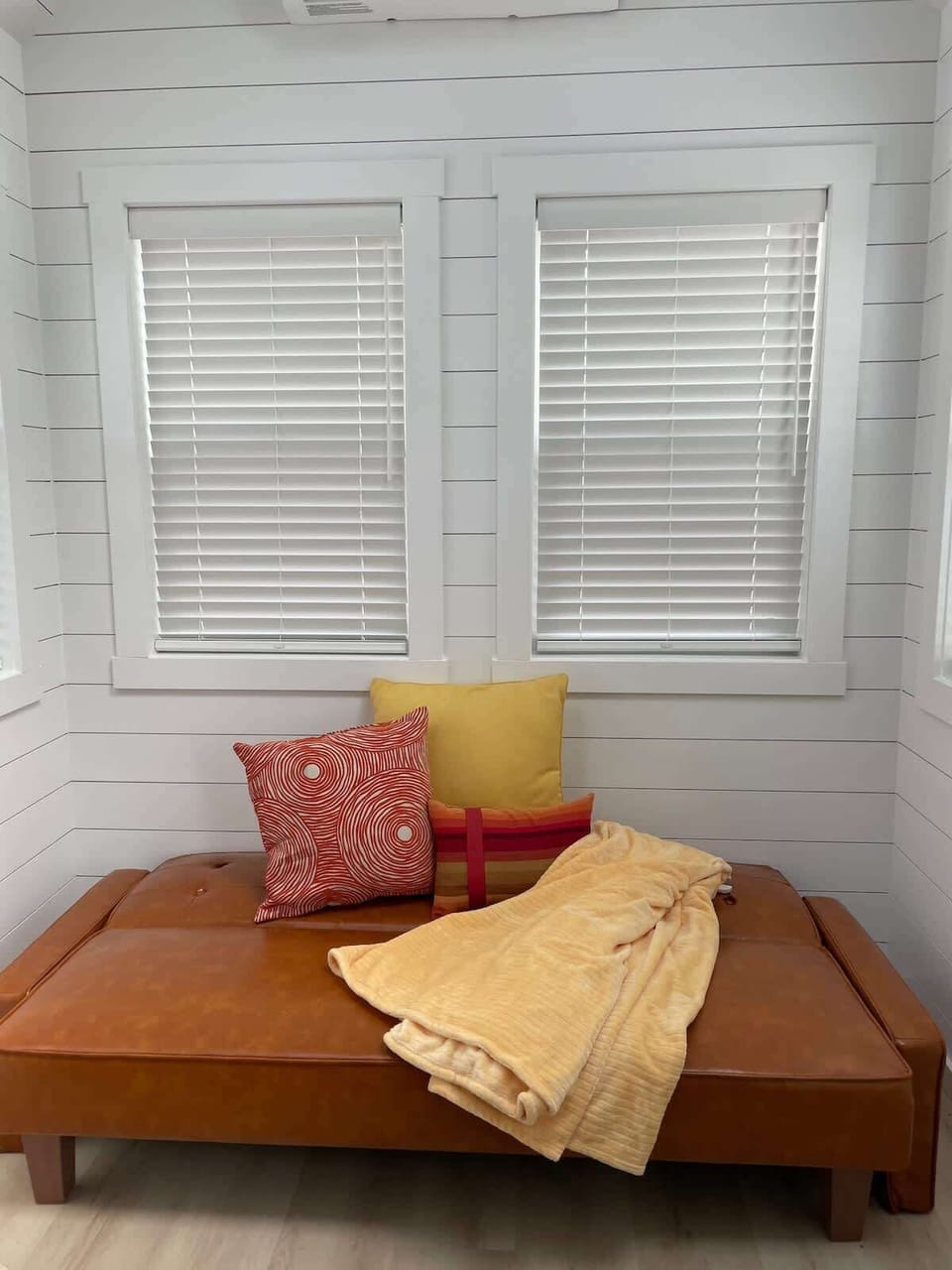 Bright lounge area with cozy seating, accent pillows, and large windows bringing in natural light. A comfortable space to relax, enjoy morning coffee, or unwind after exploring Zion and Southern Utah.