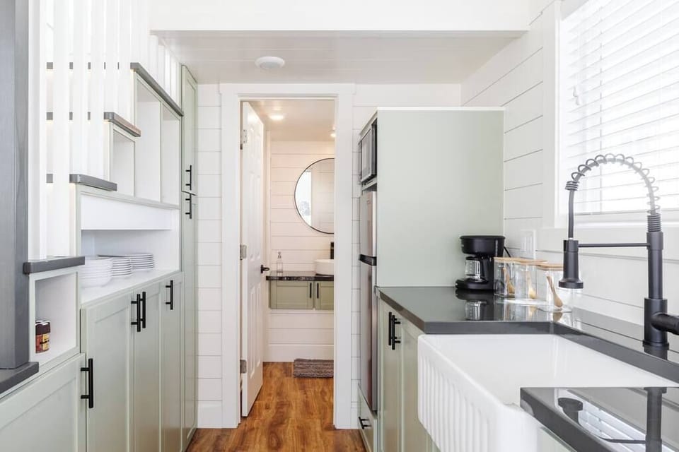 The kitchen is fully equipped with a refrigerator, freezer, microwave, cooktop, and sink with hot/cold water. Enjoy coffee from the coffee maker and ample counter space. Essentials include cookware, dishes, utensils, and plenty of storage cabinets.