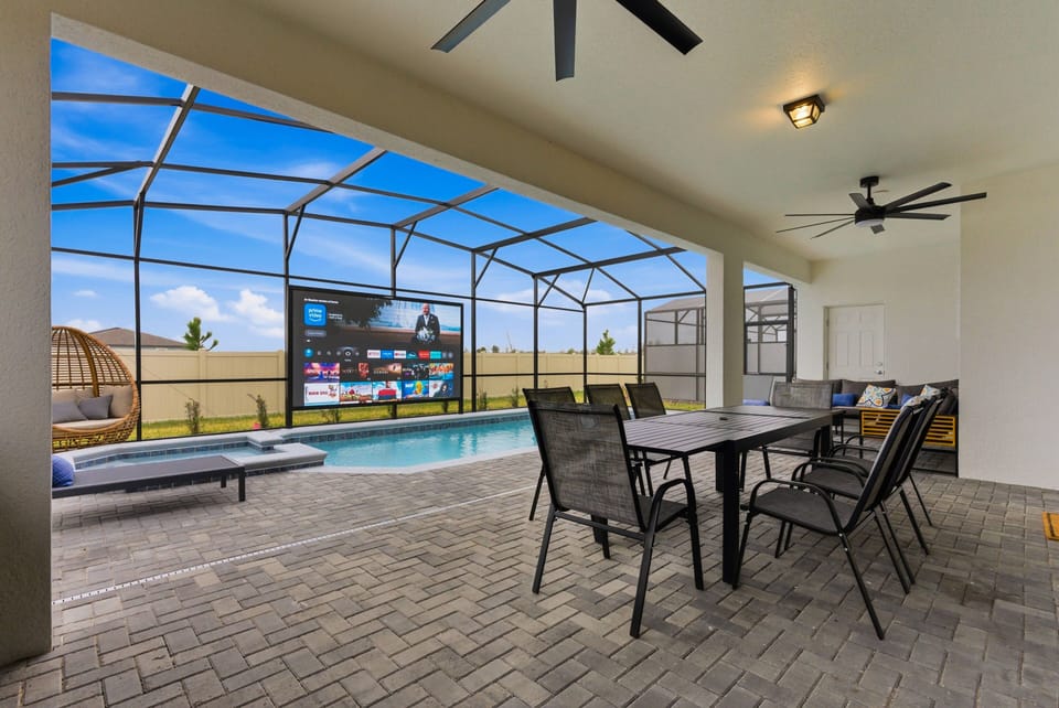 Step outside to a lovely patio featuring a sleek dining set perfect for al fresco meals. Enjoy the glistening pool under the open sky, with a screened enclosure for added comfort and relaxation in the fresh air.