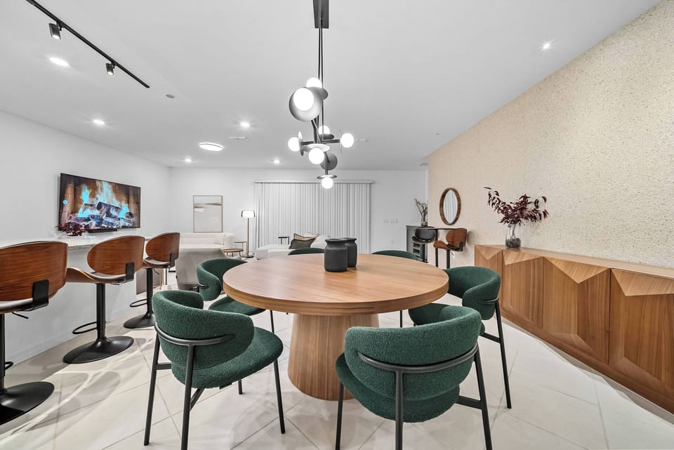 Gather around the spacious wooden dining table, surrounded by vibrant green chairs. The warm glow of the modern lighting above enhances the room's sleek design, creating the perfect atmosphere for cozy evenings with loved ones.