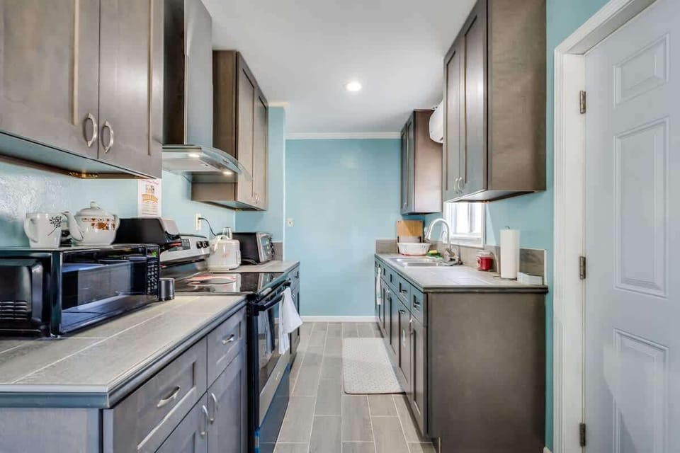 A fully stocked kitchen with microwave, stove/oven, rice cooker, and convectional oven. 