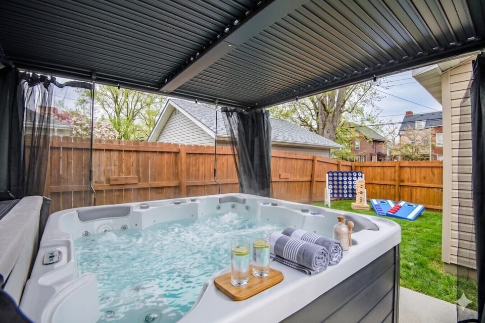 Covered Hot Tub Retreat: Unwind in the spacious, heated spa regardless of the weather while enjoying the privacy curtains and outdoor entertainment area.
