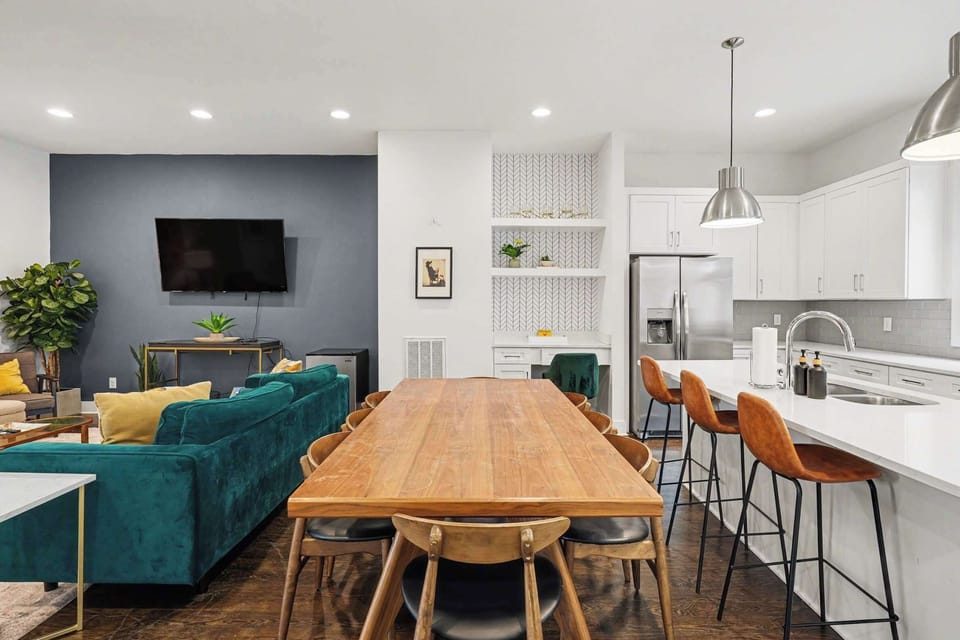 Bright dining and chef’s kitchen with island seating, pendant lights, and coffee bar. | Unit B
