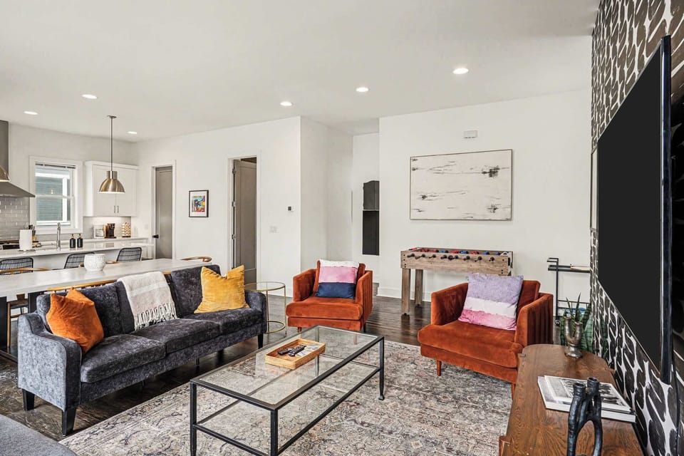 Open-concept living room with plush seating, large windows, and a chef's kitchen.