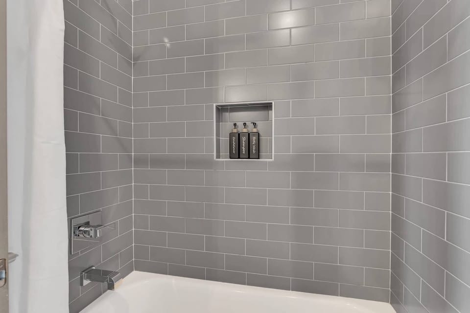 Guest bathroom w/ single vanity and shower/tub combo off living room and kitchen
