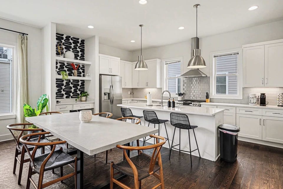 Bright dining and chef’s kitchen with island seating, pendant lights, and coffee bar. | Unit A