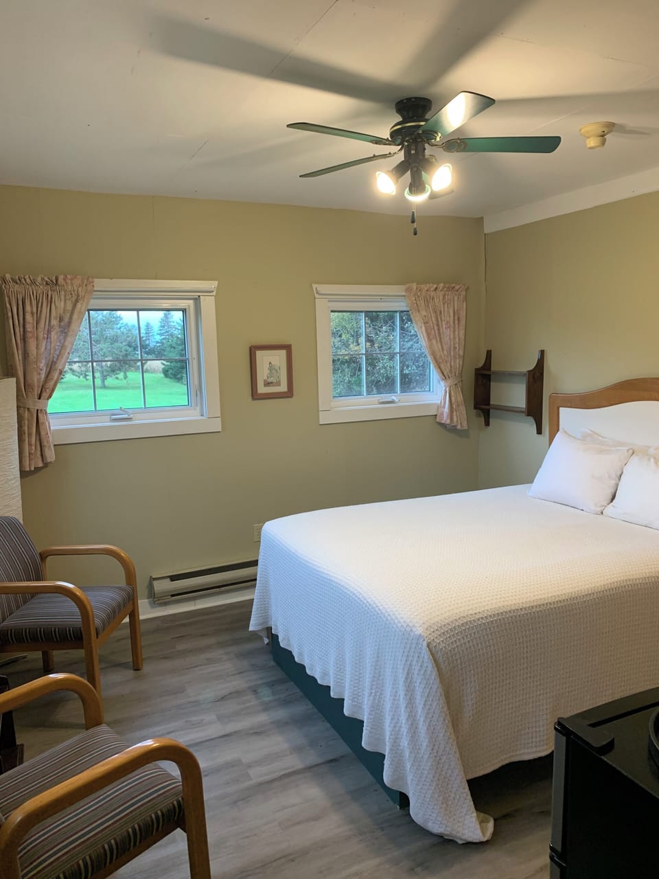 Barn 1 is a ground level corner room with four windows, a queen bed, ceiling fan and a refrigerator