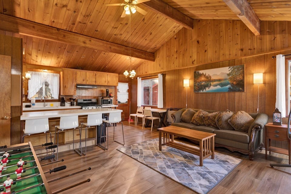 Cozy mountain living room with a stone fireplace, comfy seating, and smart TV—perfect for relaxing evenings, movie nights, and warm cabin vibes after outdoor adventures.