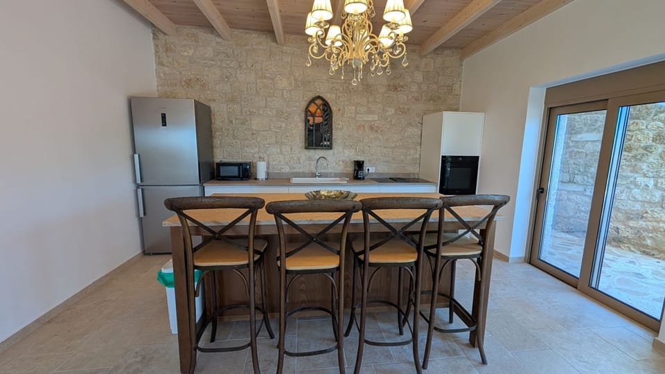 Modern kitchen at Achilles Cottage with Mani stone backsplash, breakfast bar and crystal chandelier