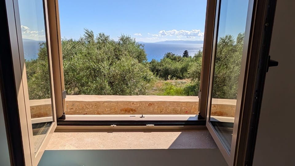 Open window at Achilles Cottage framing the Gulf of Messenia through Kardamyli olive groves