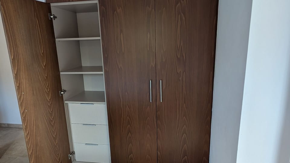 Built-in wardrobe with shelving and drawer storage in the Achilles Cottage bedroom