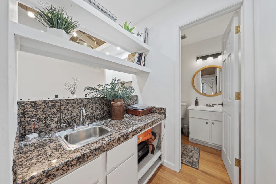 Compact kitchen corner with granite countertops and open shelving.
