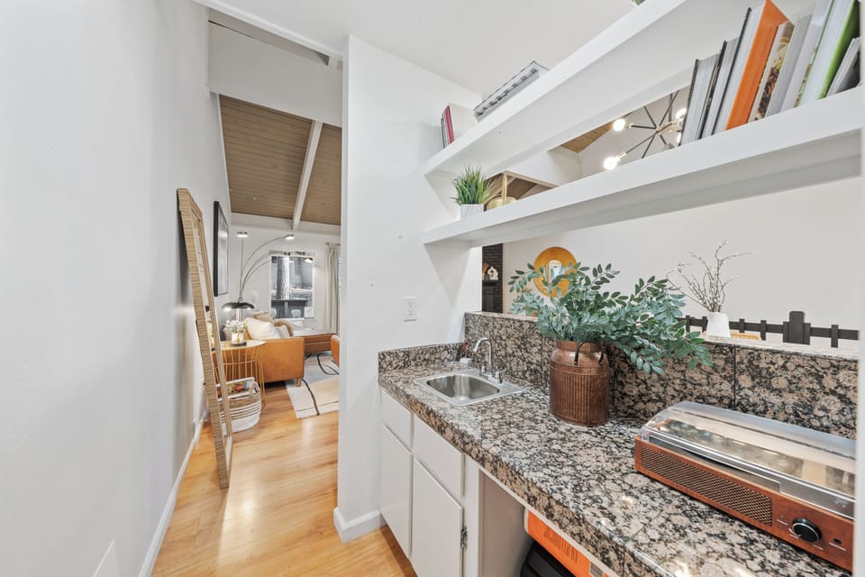 Kitchen hallway with granite counters, white cabinetry, and wood flooring.