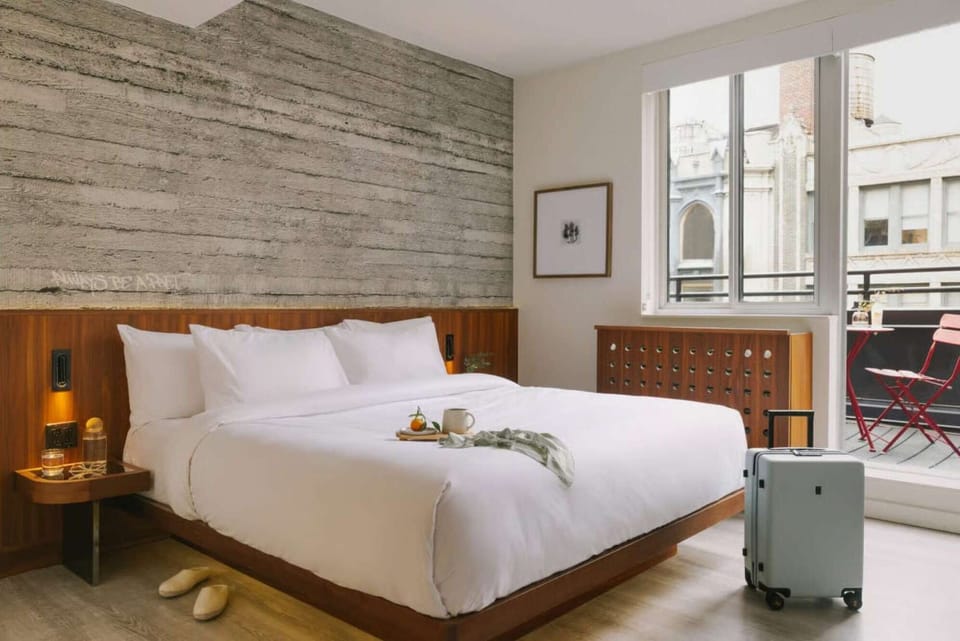King bed facing balcony doors, side table, and compact luggage