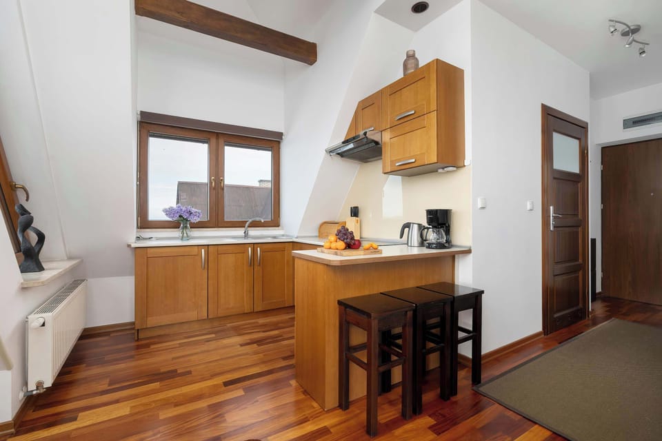 A compact kitchen with wooden cabinets, small dining table, and modern stove. The layout is efficient and designed for small-space living.