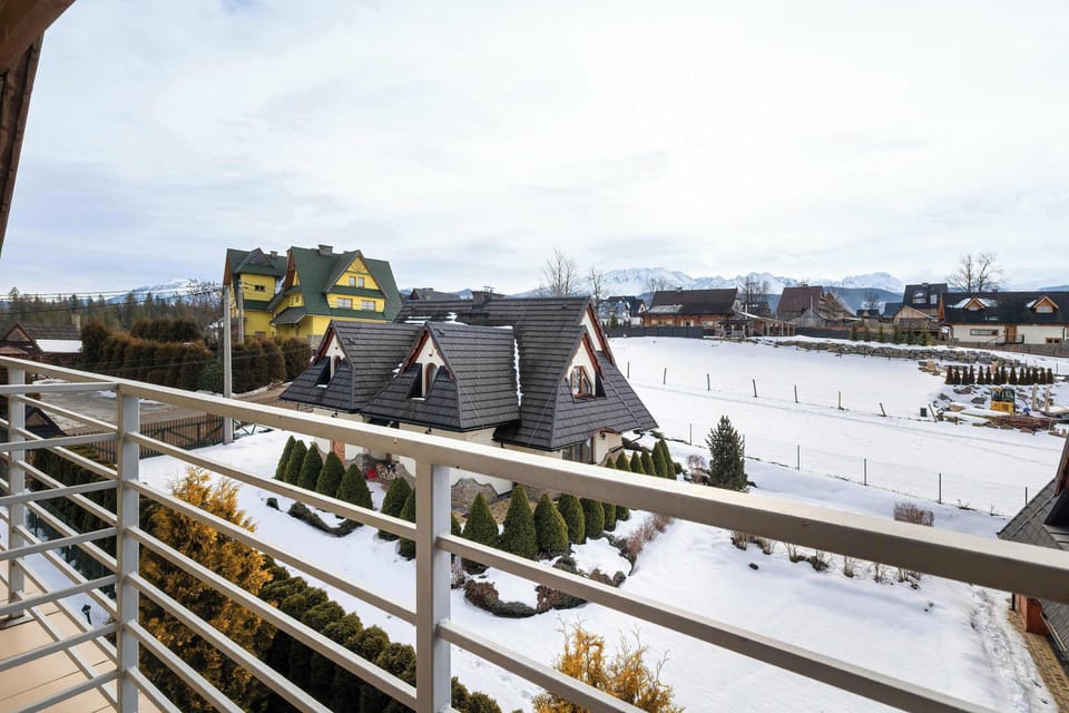 A similar balcony view overlooking rooftops and winter scenery. The sky is partly cloudy, giving the scene a crisp outdoor look.