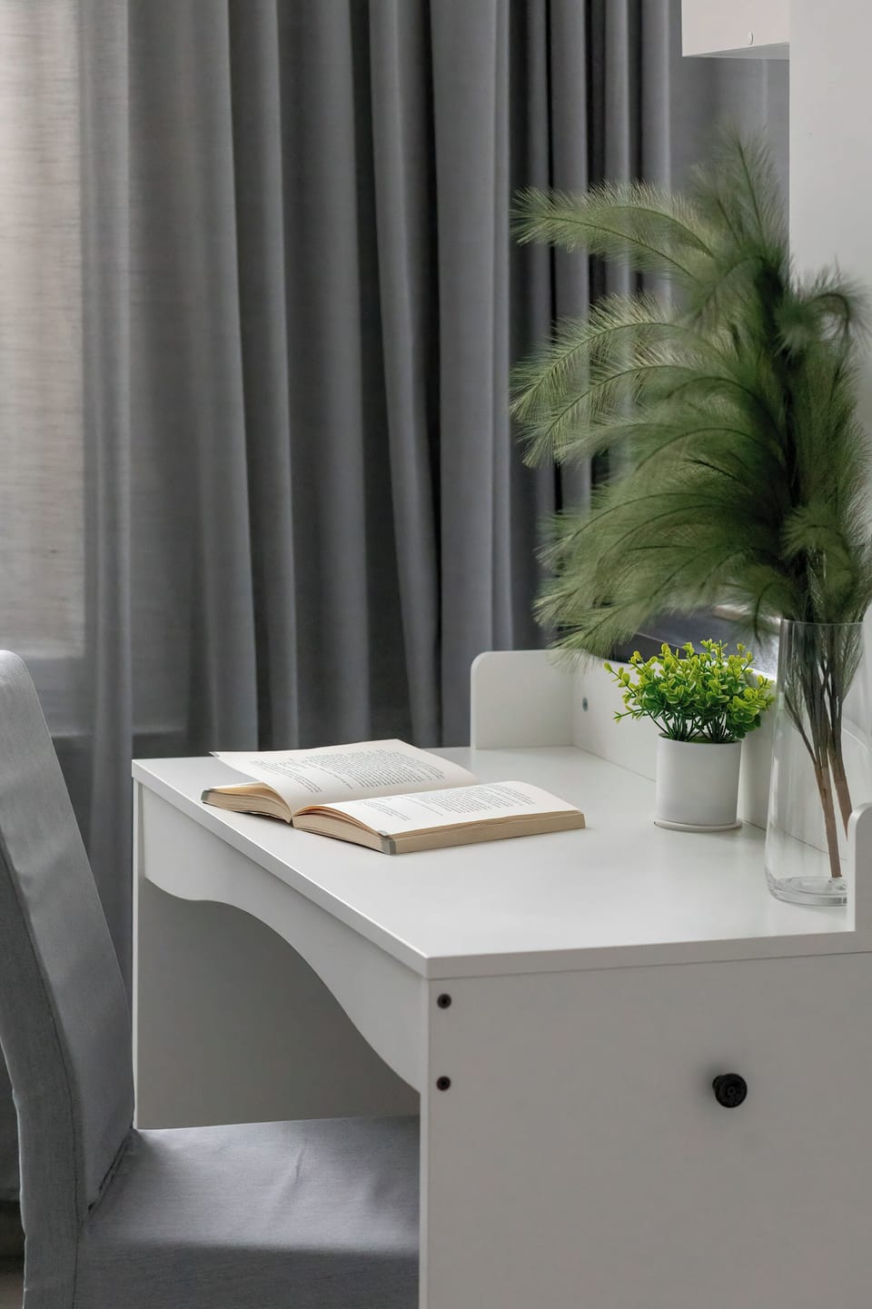 A bedroom desk by the window with a small plant on top. Natural light makes the workspace bright and pleasant.
