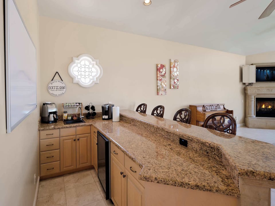 Coffee bar featuring a drip and keurig coffee maker and bar seating for 4 guests.