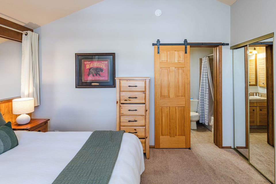 Your cozy bedroom features a comfortable bed, warm wood accents, and charming barn door leading to your private bathroom.