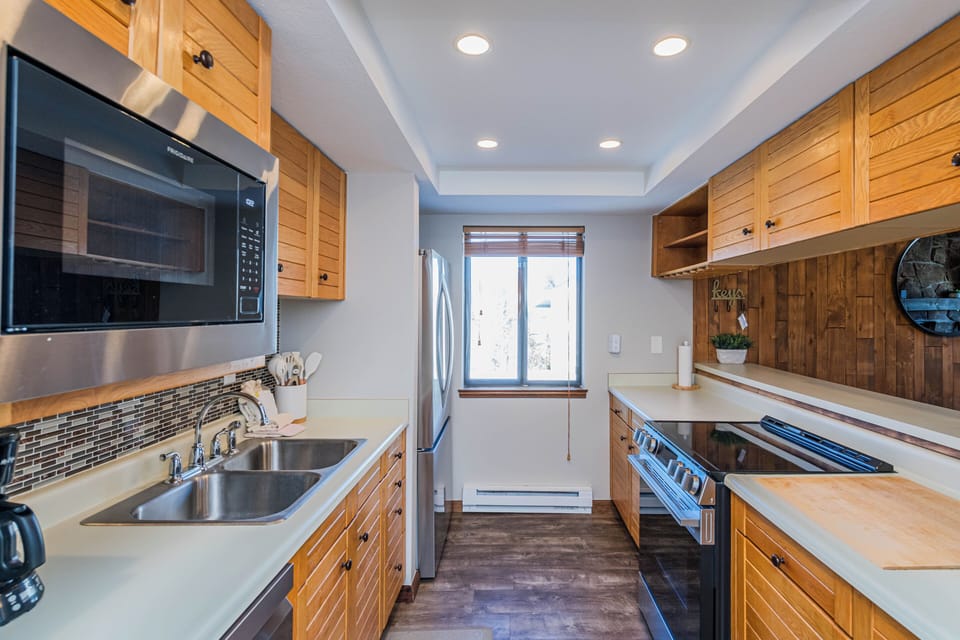 Step into your fully equipped galley kitchen with warm wood cabinets, stainless appliances, and ample counter space for preparing memorable meals.