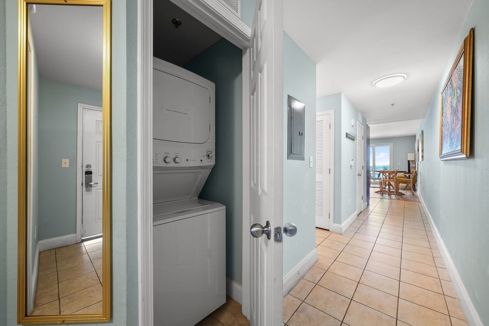 hallway with tiled floors and a stacked washer and dryer closet