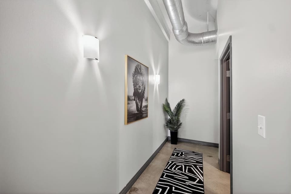 Stylish Hallway: Clean, gallery-like corridor enhanced by modern wall sconces, bold artwork, and a graphic runner rug for a polished transitional space.