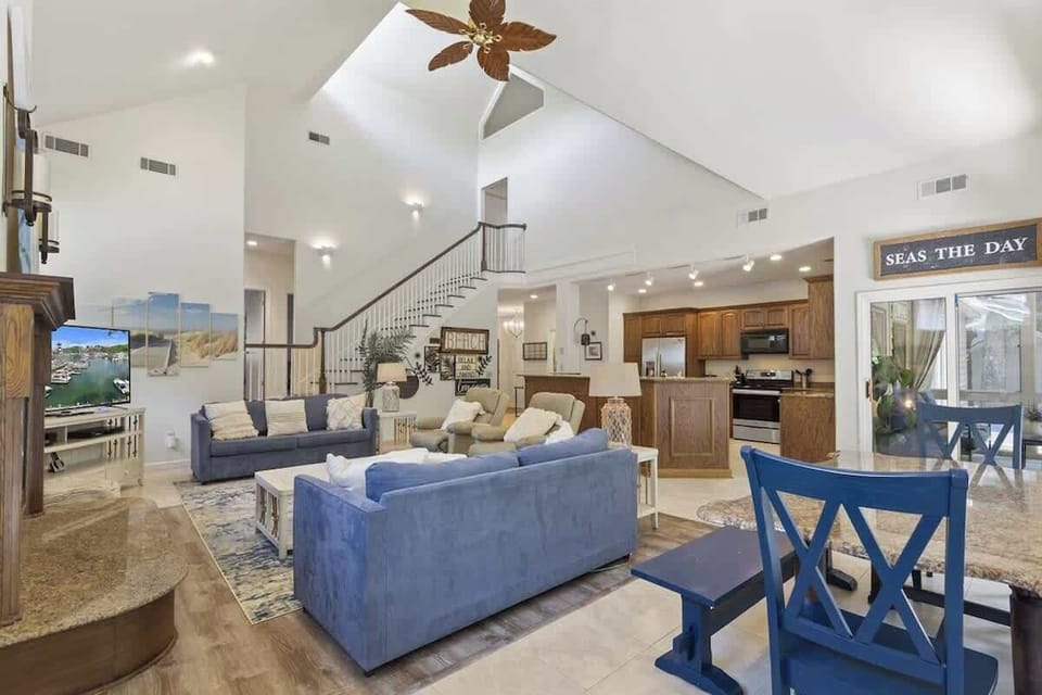 Relax in your spacious open-concept living room with soaring ceilings, coastal blue furnishings, and a fully equipped kitchen ready for your culinary adventures.