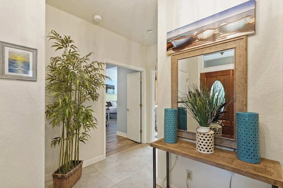 Step into your stylish coastal entryway where warm wood accents and tropical touches create an instant sense of relaxation and welcome.
