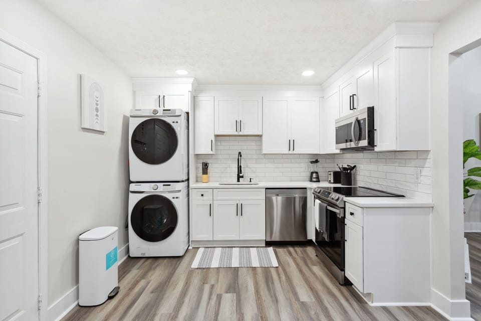 All-white kitchen is fully equipped with stainless steel appliances 
