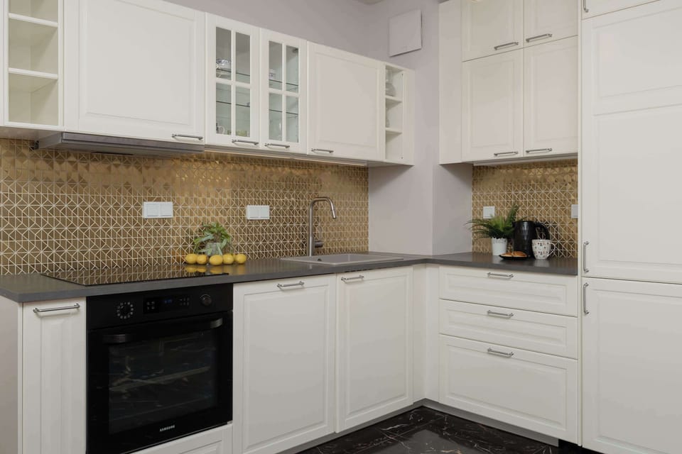 Modern kitchen with white cabinets, tiled backsplash, and built-in oven.