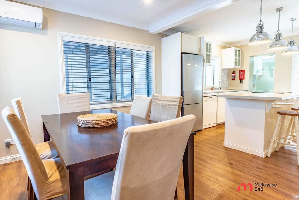 Dining area with wooden table and upholstered chairs beside the kitchen.