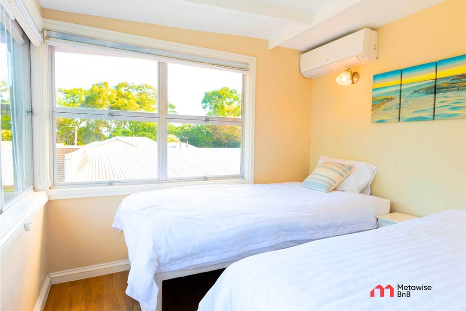 Bedroom with two single beds positioned side by side near a large window.