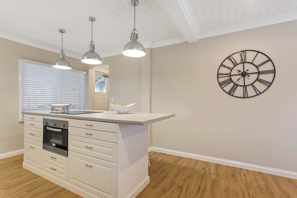 Kitchen with island bench and decorative wall clock feature.