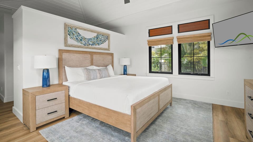 Rest peacefully in your bright bedroom featuring warm wood furnishings, crisp linens, and tropical garden views.