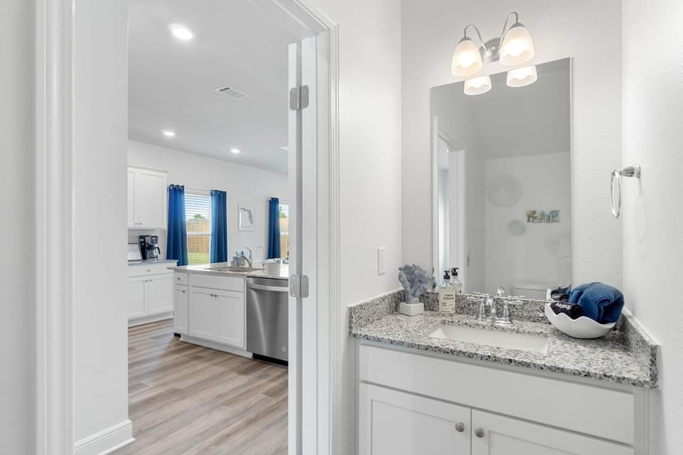 Chic & Modern Half Bath: Step into this stylish half bathroom, featuring sleek fixtures, a contemporary sink, and pristine finishes. Perfect for freshening up after a day at the beach. Conveniently located on the first floor.