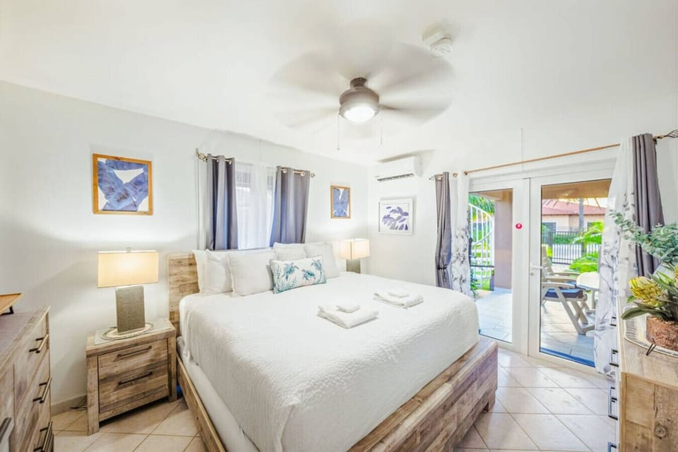 Bedroom 1 features a plush King-size bed, cooling A/C, and sliding glass doors that open directly to the patio.